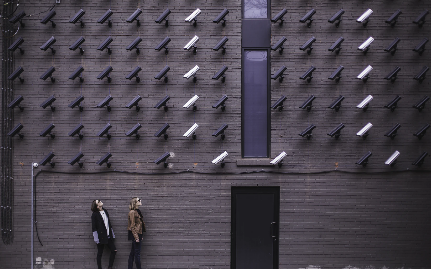 Integrated camera monitoring across a secured building facade